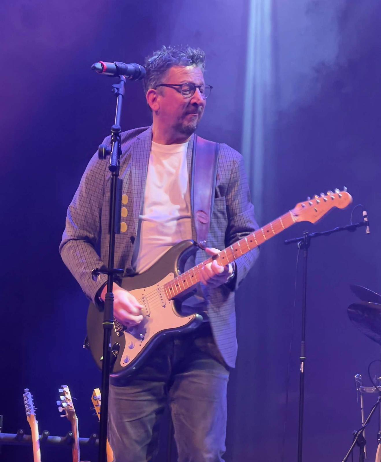 Benny Guitar Smith playing his electric guitar on stage under blue lights